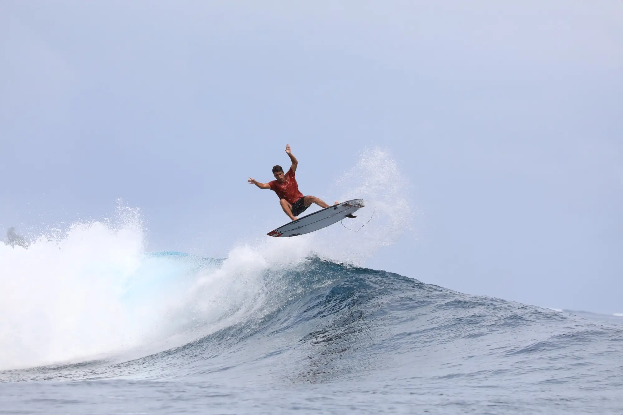 Surfer launching a full aerial above the lip of a wave