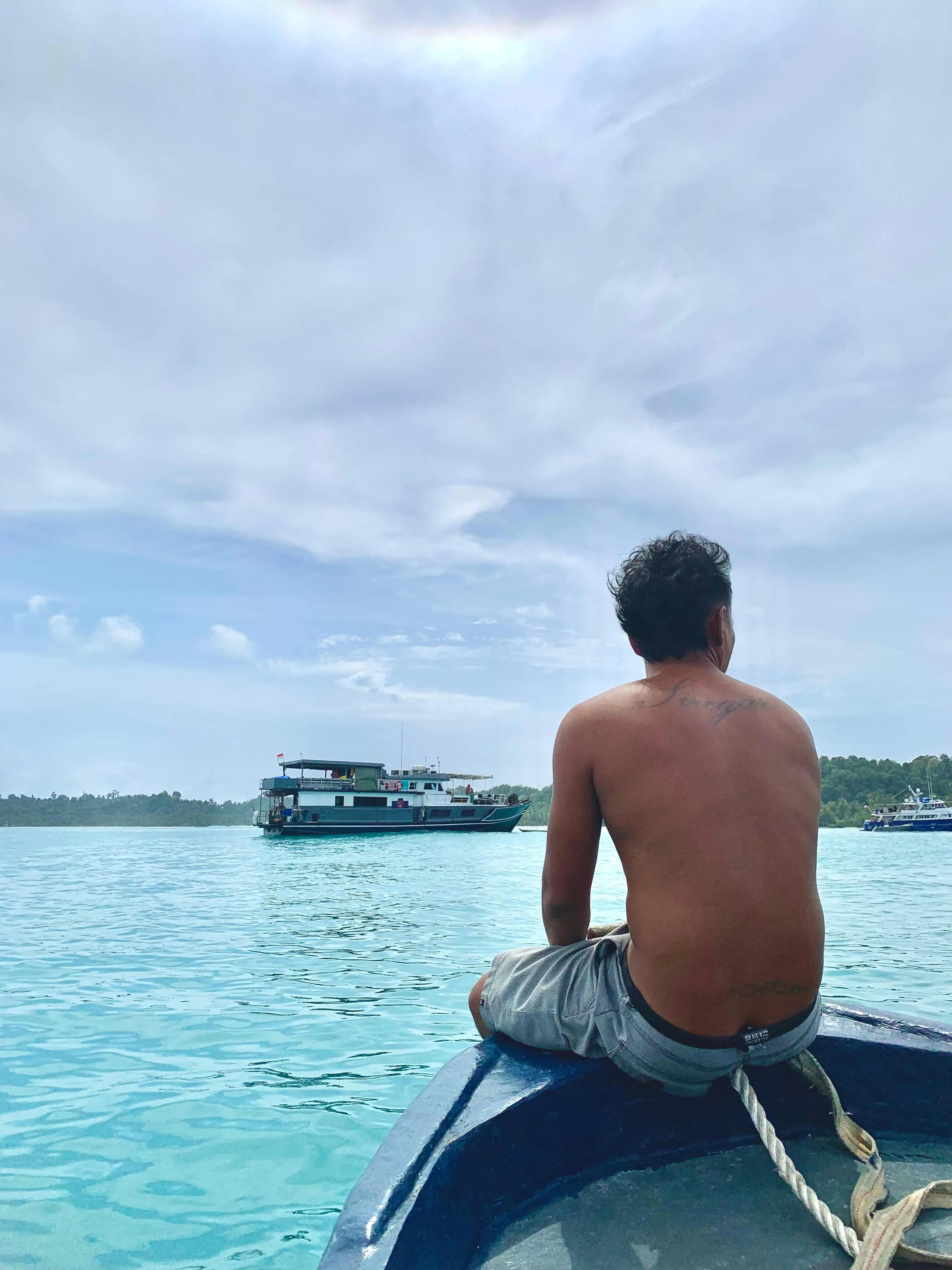 A crew member on the tender heading back to the Ombak Kabau at anchor