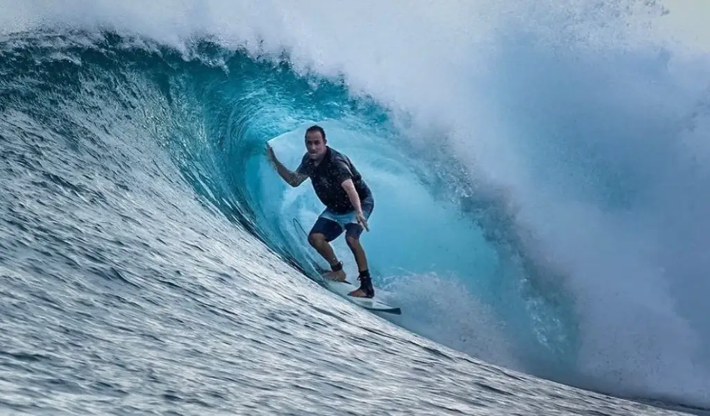 Surfer crouched mid-barrel with a hand on the wave face