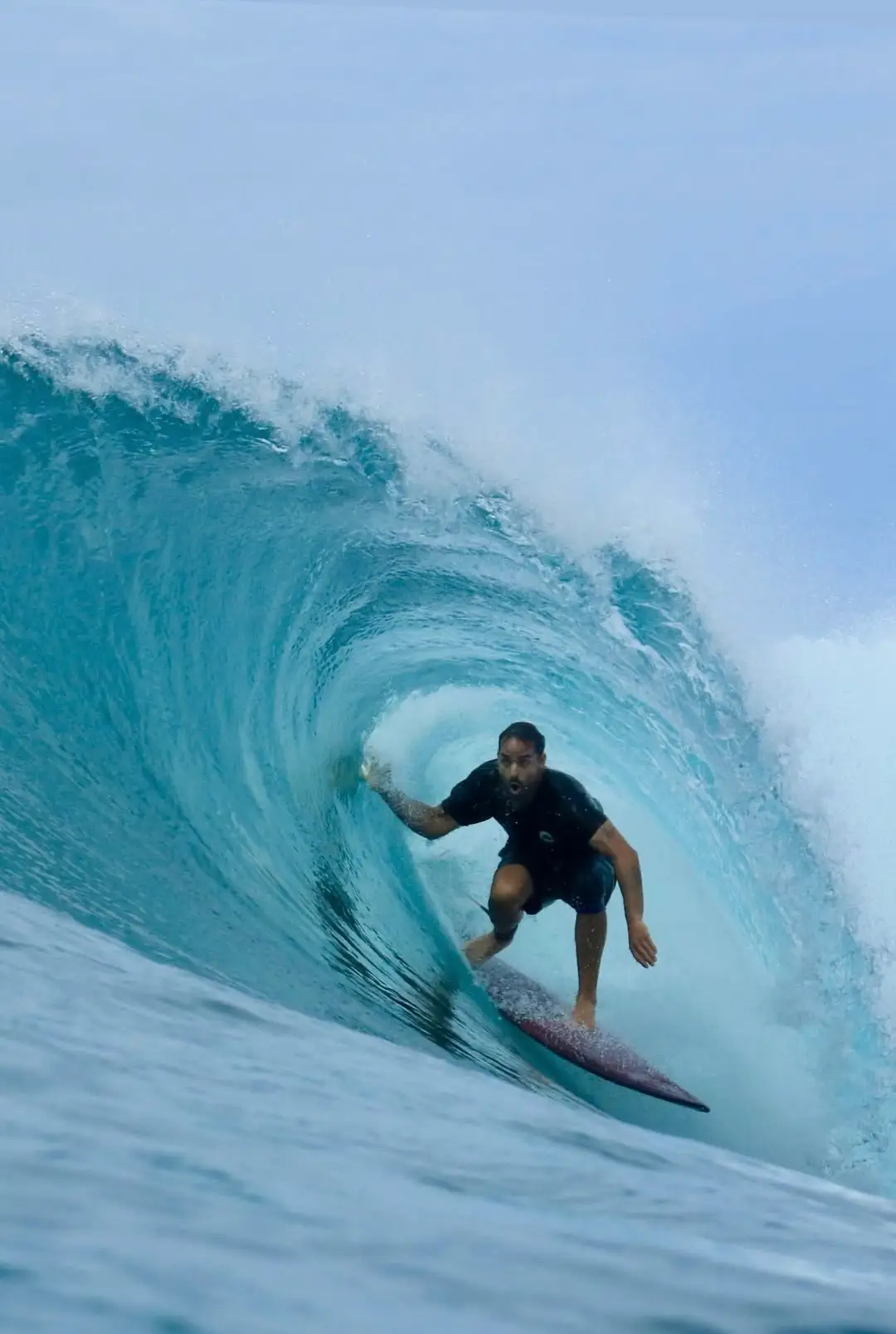 Surfer crouched inside a spinning turquoise barrel at Macaronis