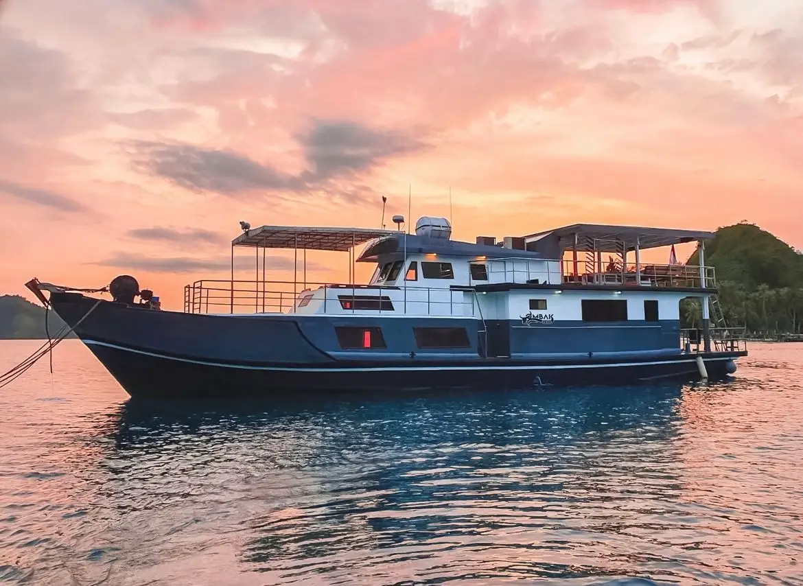 The Ombak Kabau at anchor under a pink and orange sunset