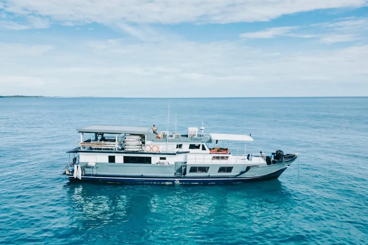 The boat anchored over clear turquoise shallows