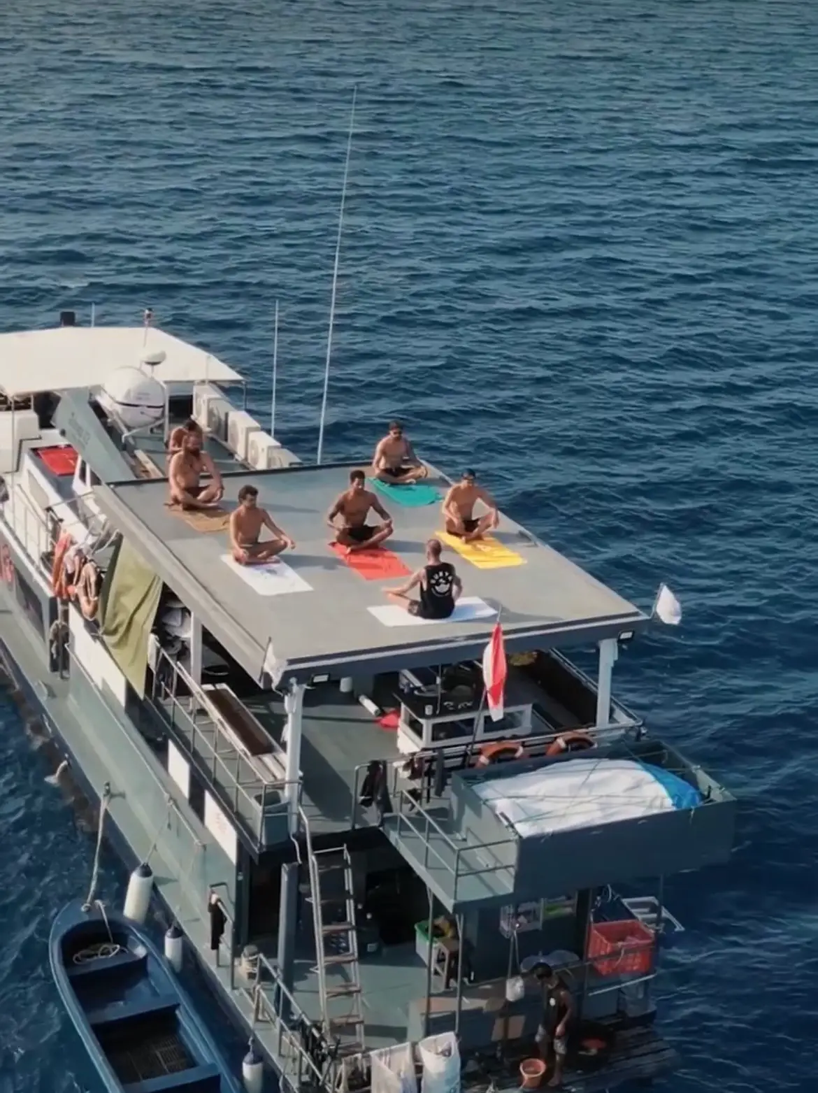 Guests stretching on colourful towels on the top deck, seen from above