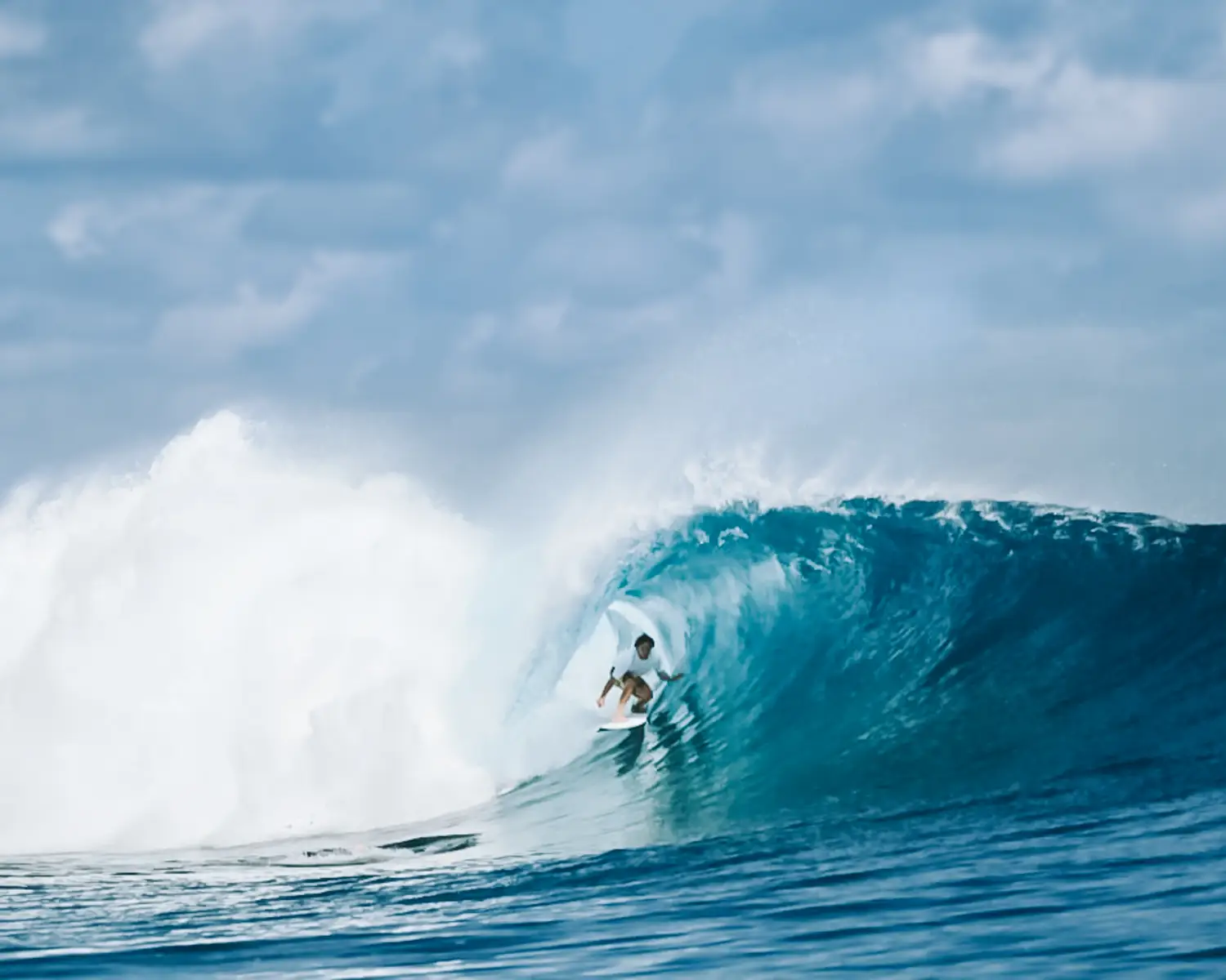 Surfer tucked inside a wide-open turquoise barrel in the Mentawai Islands