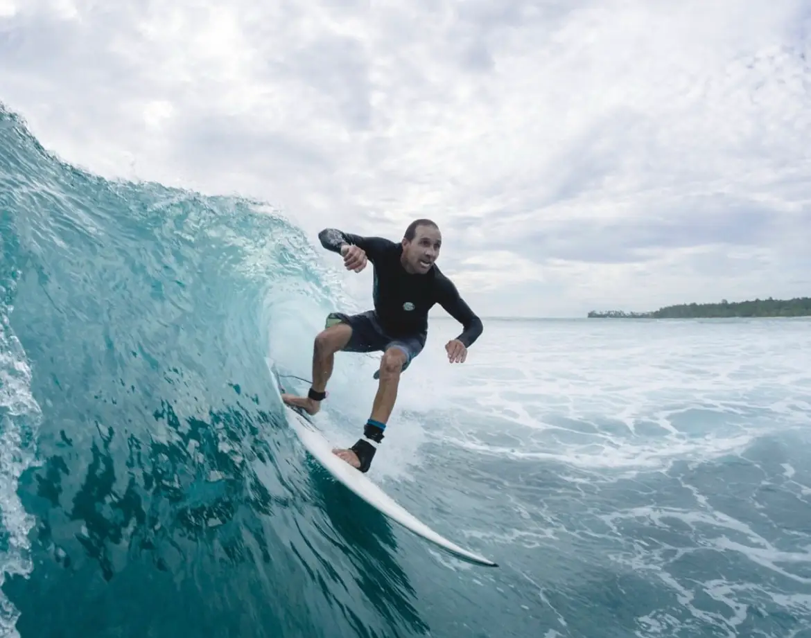 Wide-angle shot of a surfer racing along a turquoise wave face